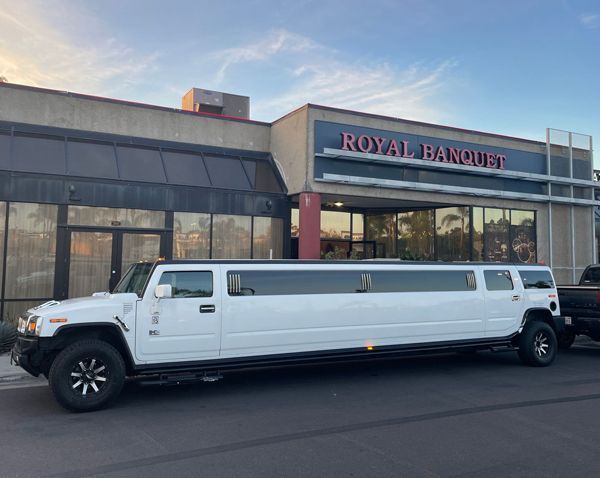 A white hummer limousine is parked in front of a building.