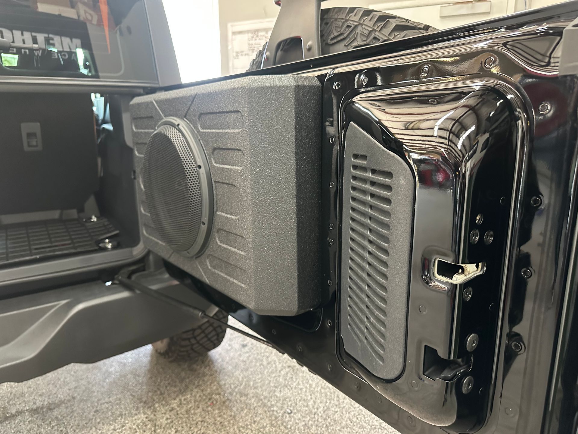 A black car with a speaker attached to the back of it.