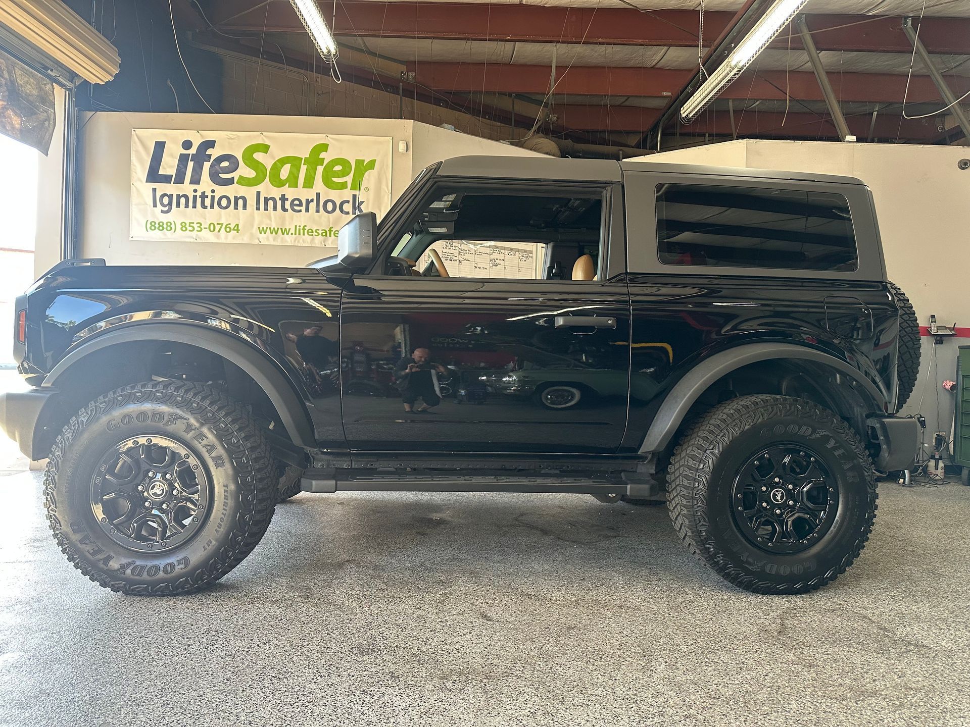 A black ford bronco is parked in a garage next to a lifesaver sign.