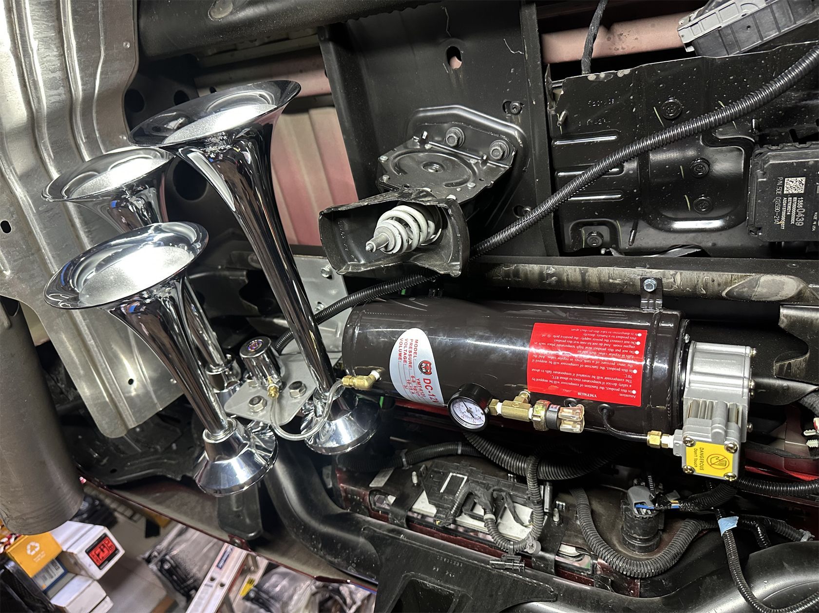 A close up of a car horn on the underside of a car.