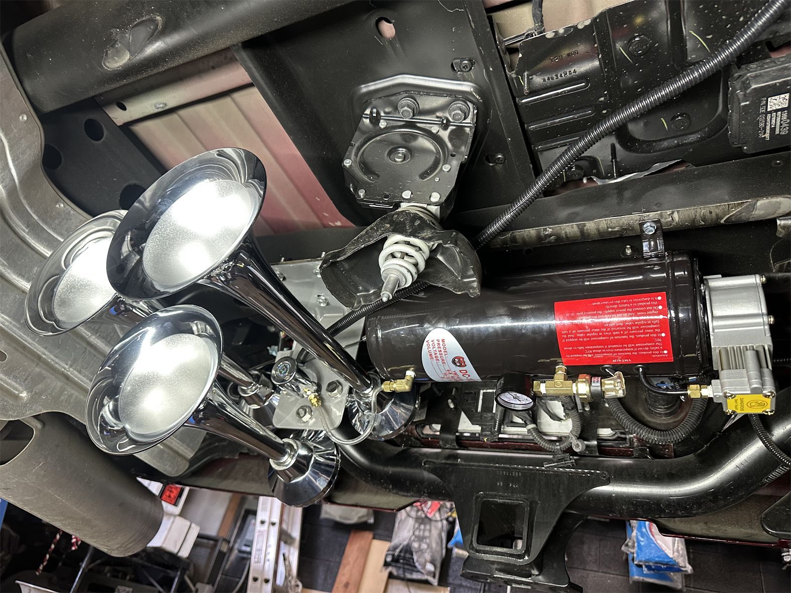 A close up of a car horn on the underside of a car.