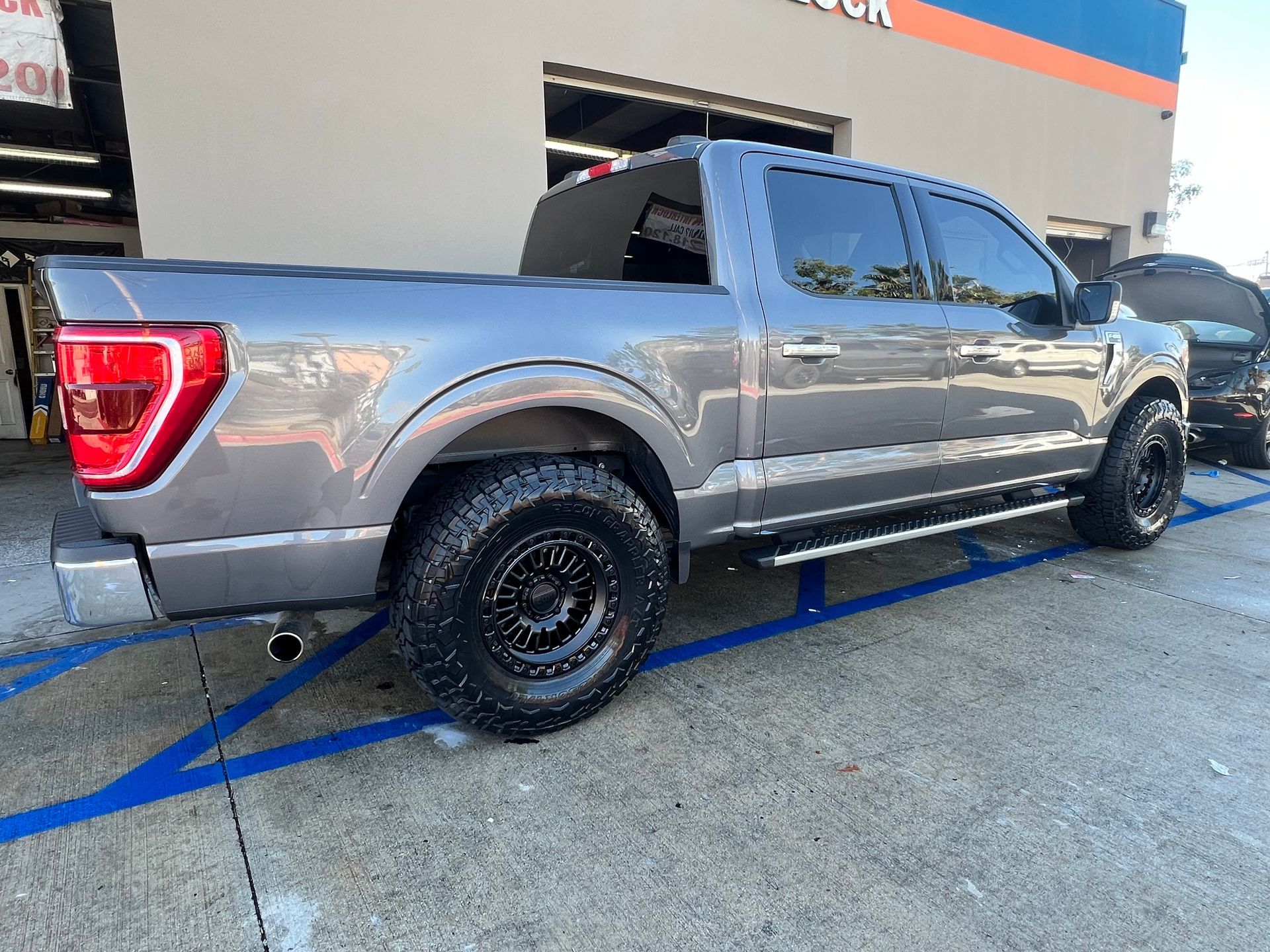 Gray pickup truck parked outside a building with black tires and tinted windows.