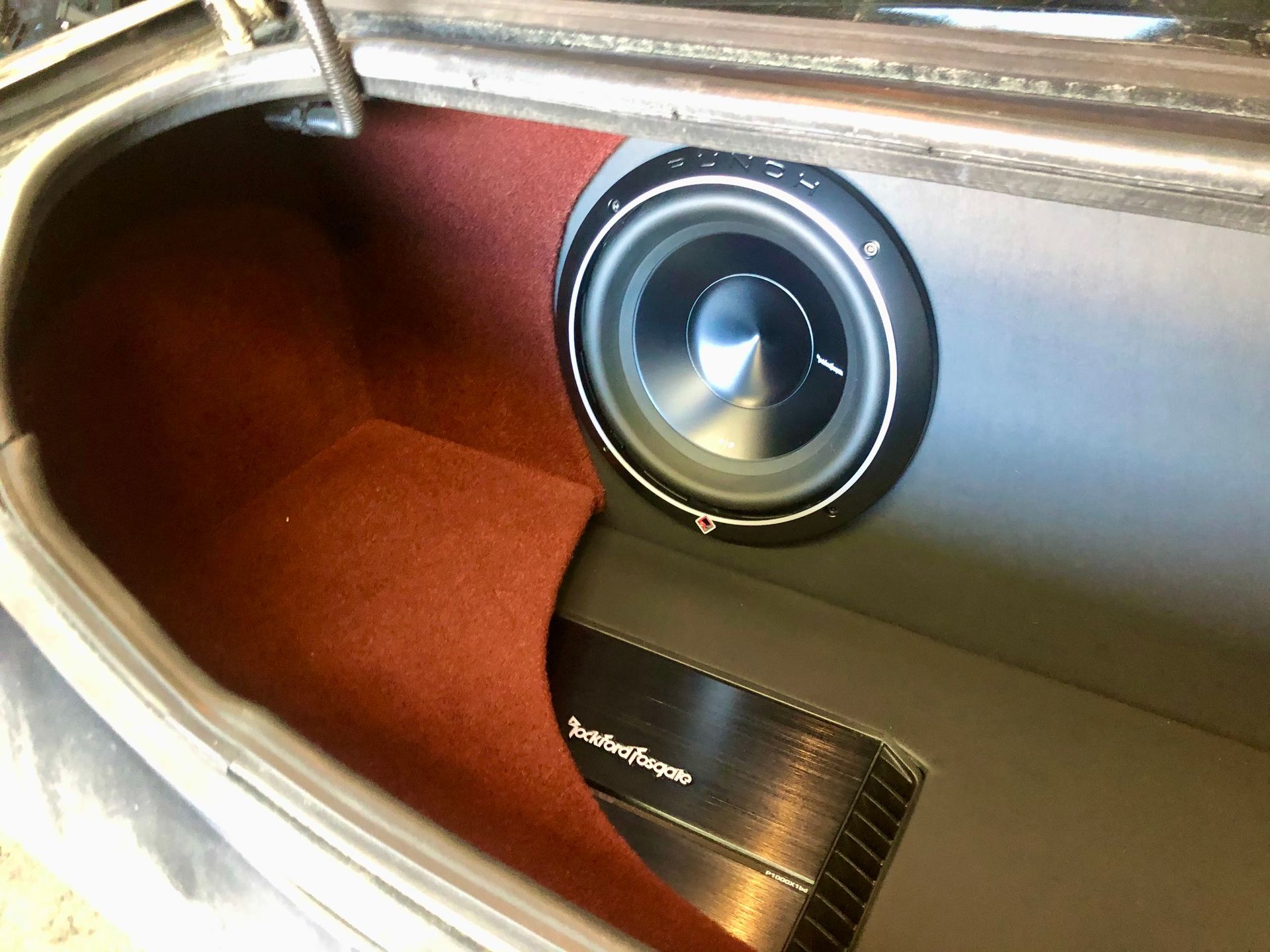 A subwoofer is sitting in the trunk of a car.