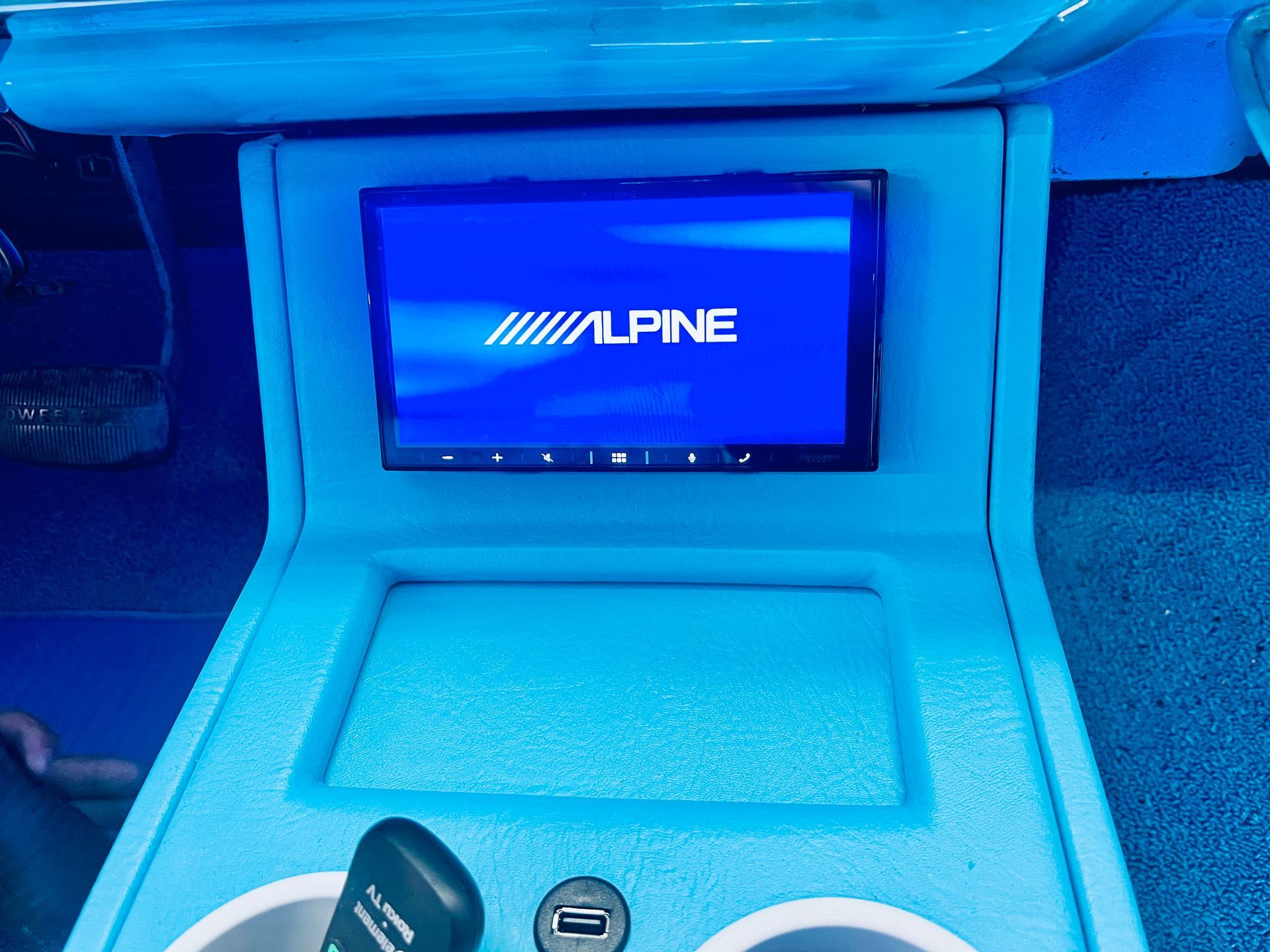 A blue car console with a alpine radio on it