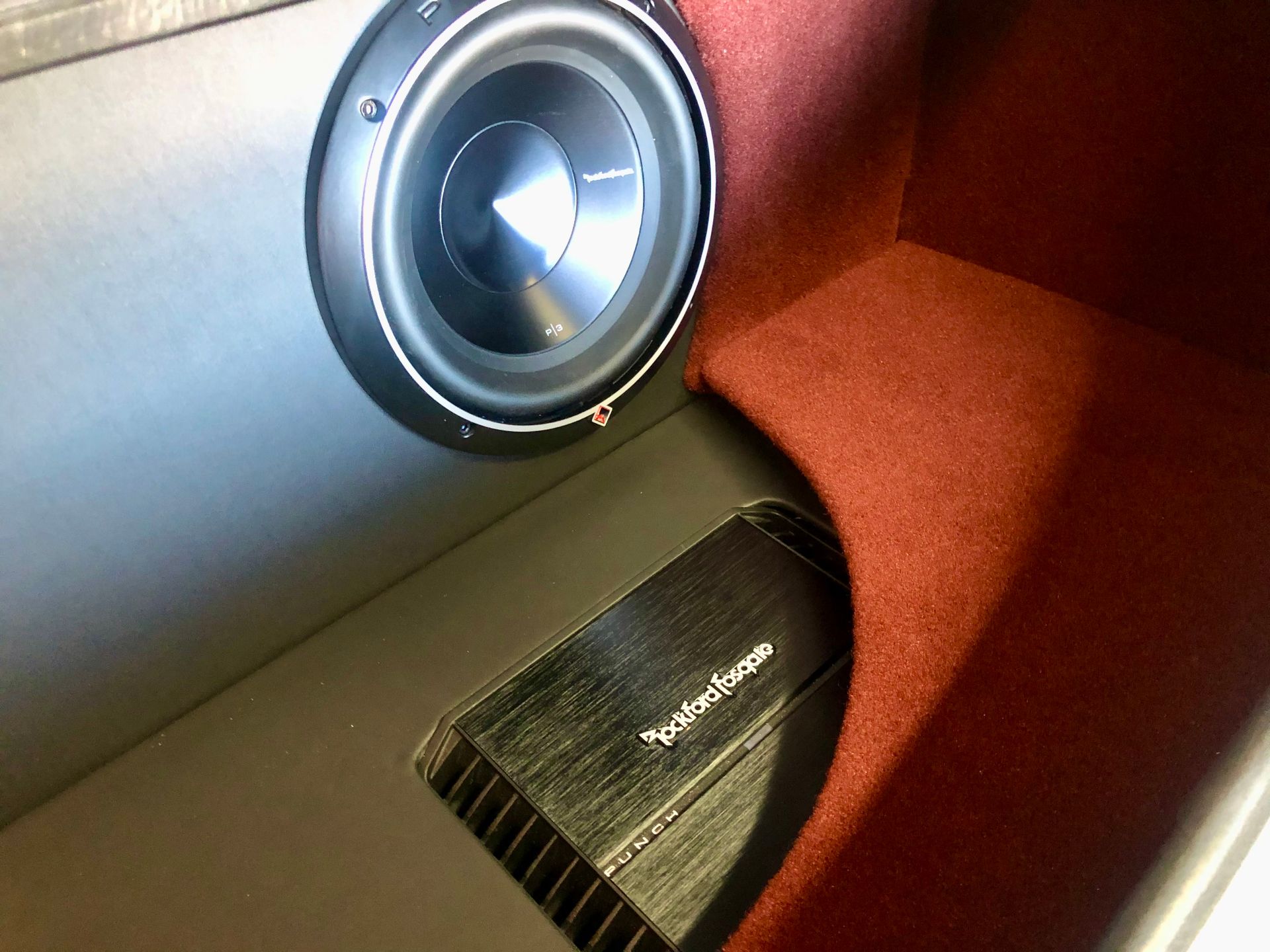 A rockford fosgate amplifier sits next to a subwoofer