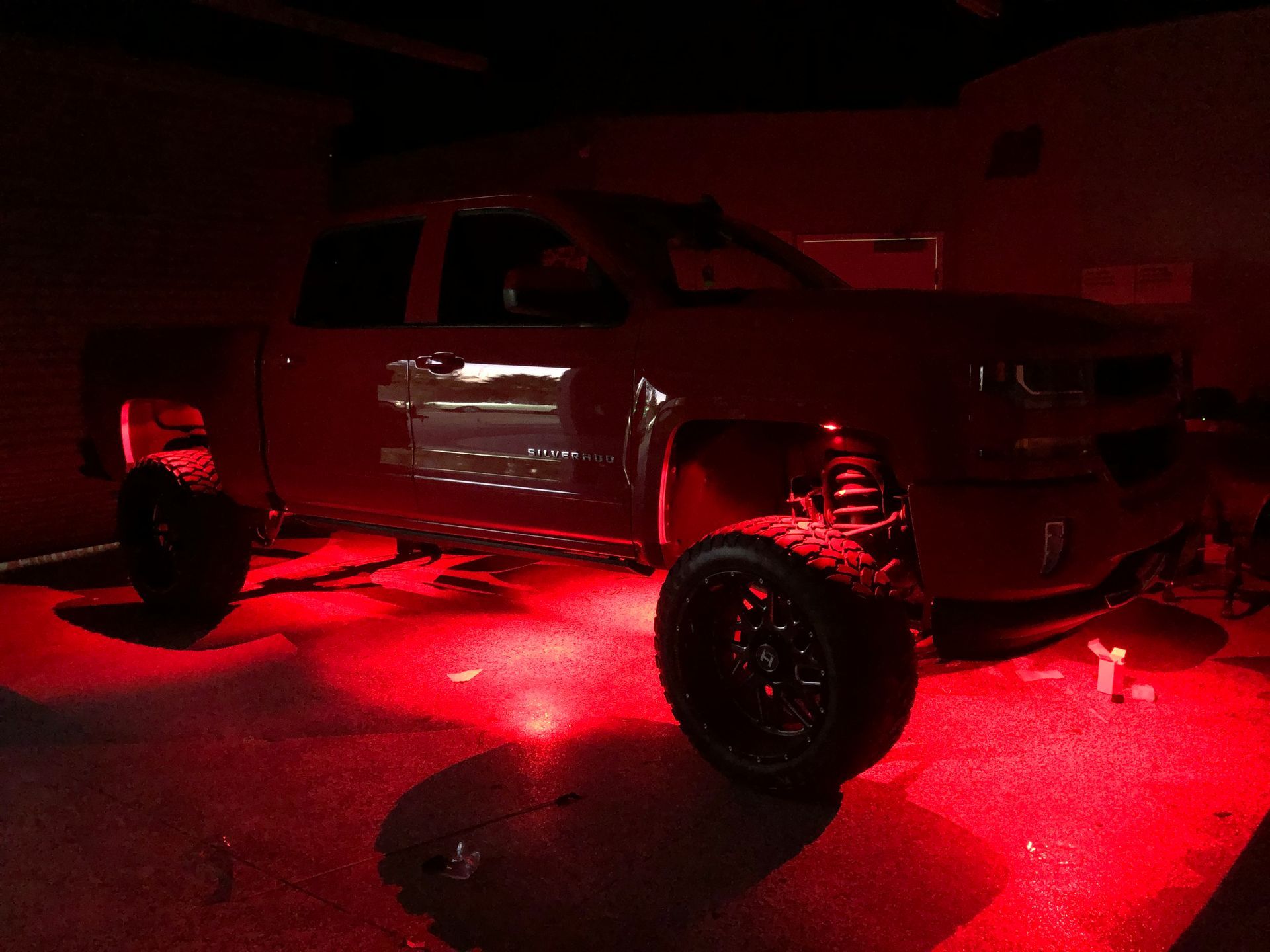 A red truck is parked in a garage with red lights on it.
