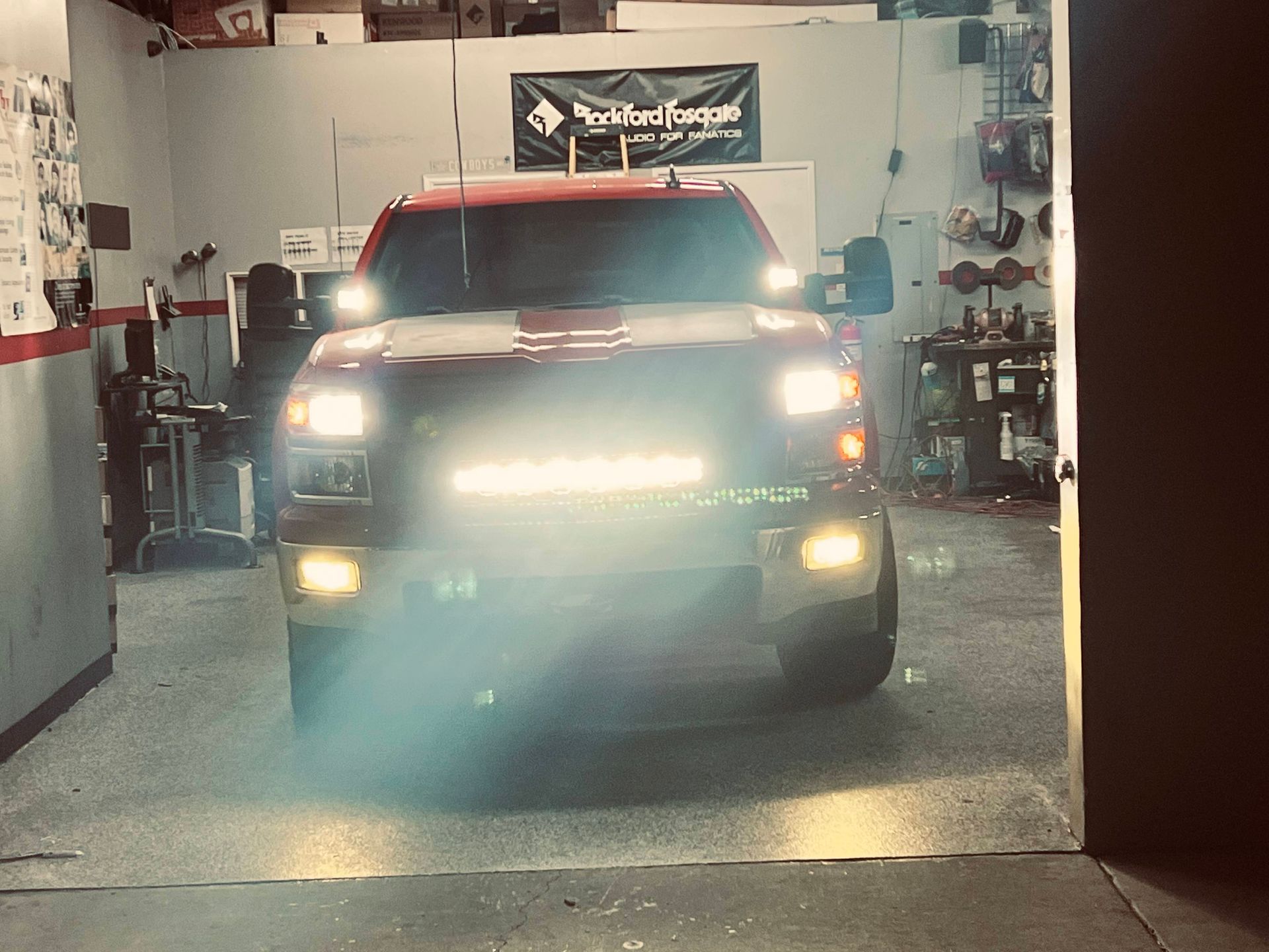 A red truck is parked in a garage with lights on