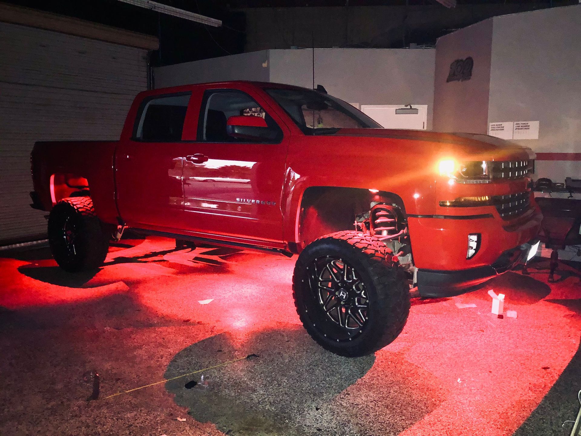A red truck is parked in a garage with red lights on it
