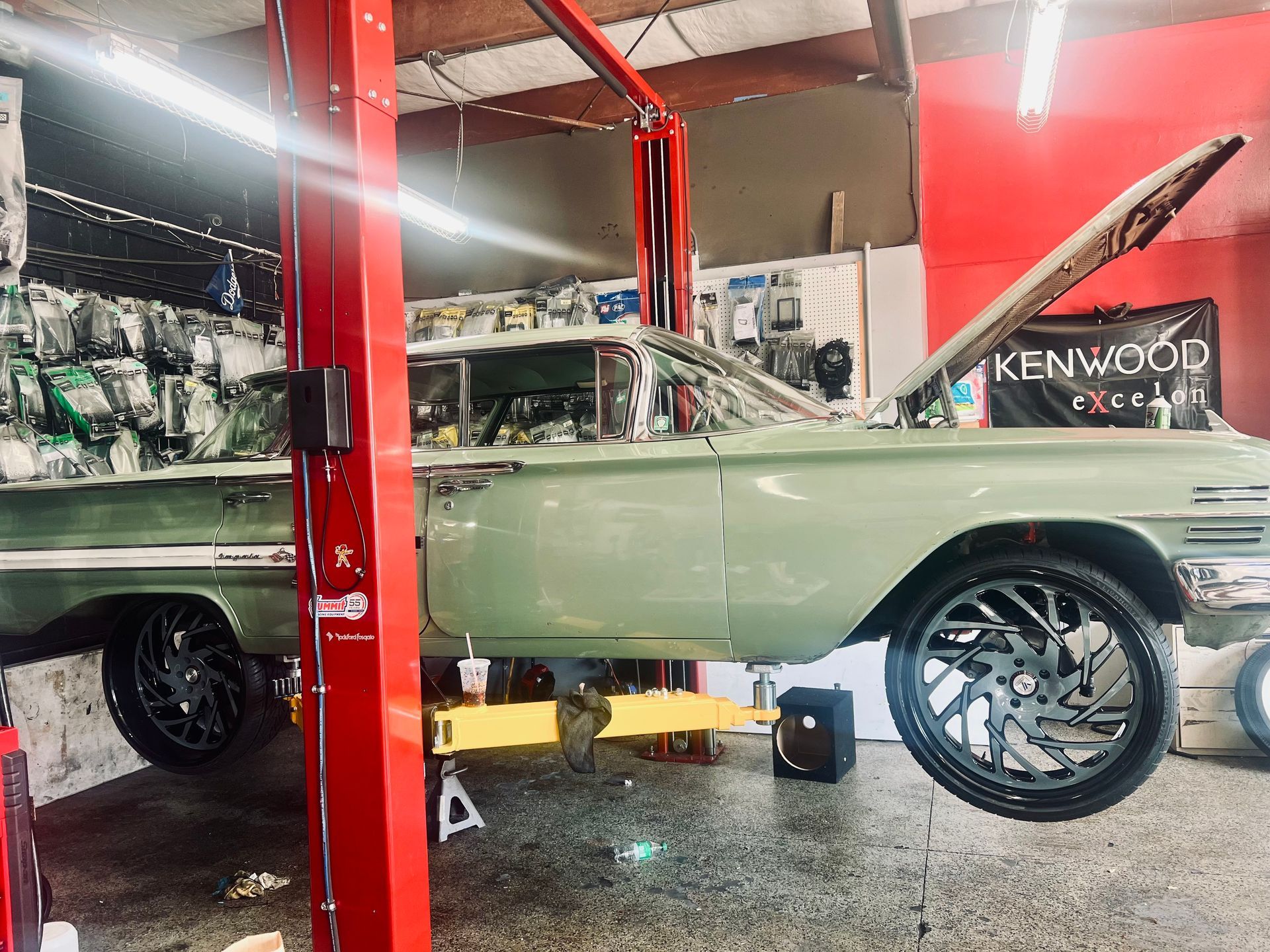 A green car is sitting on a lift in a garage.