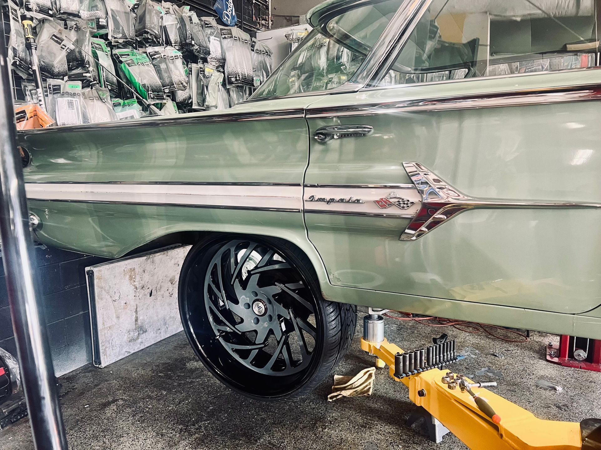 A green car is sitting on a lift in a garage.