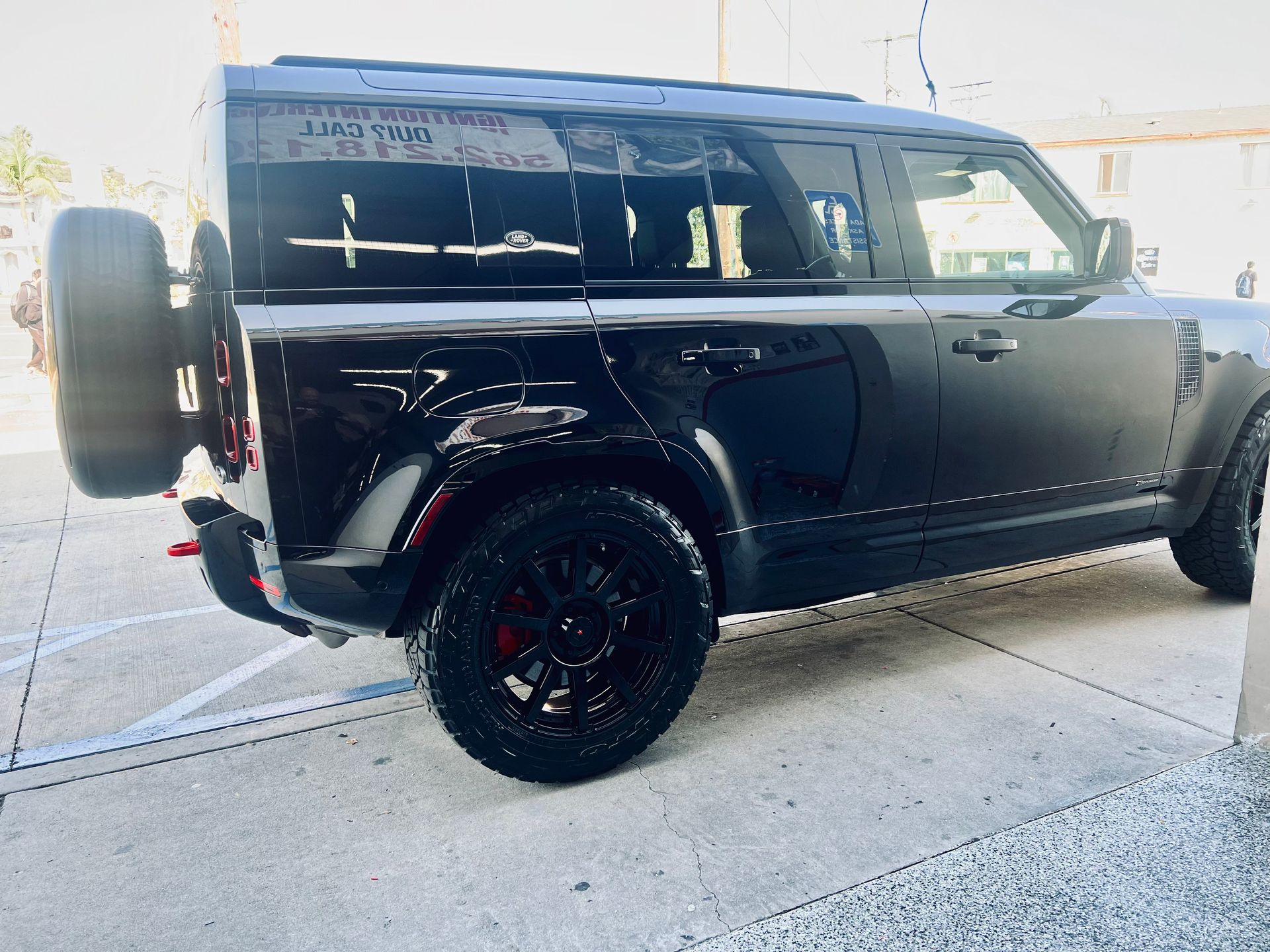 A black land rover defender is parked in a parking lot.
