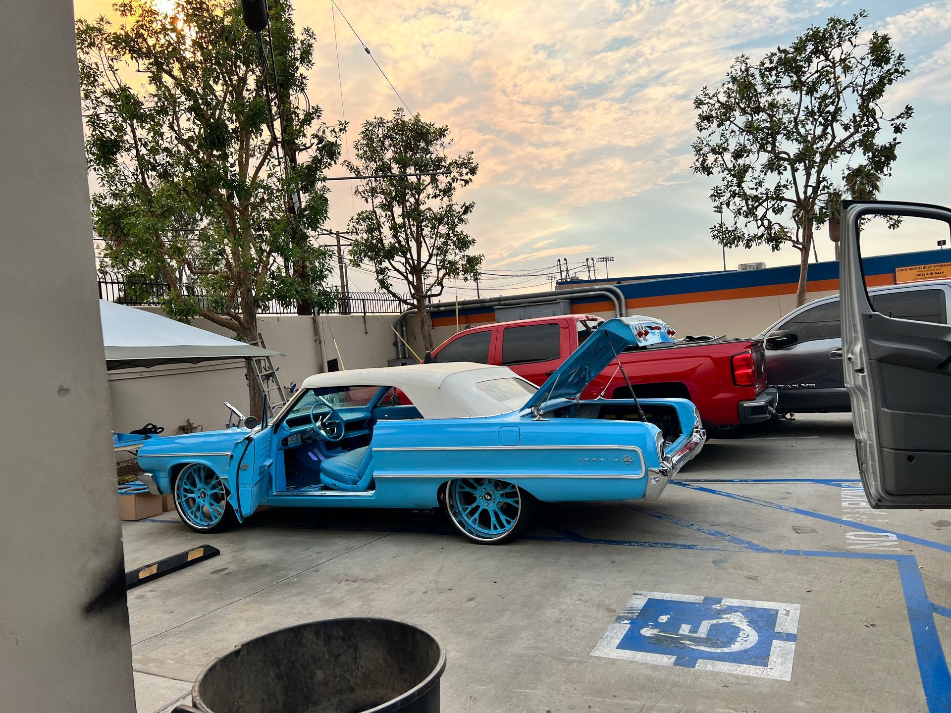 A blue car is parked in a handicapped parking spot.