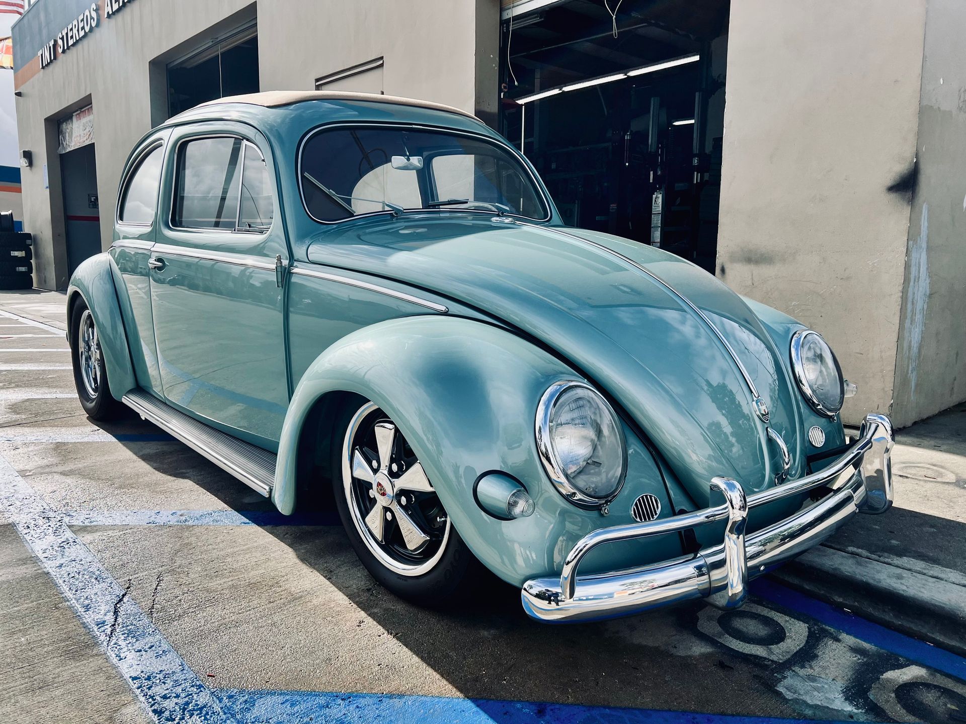 A blue volkswagen beetle is parked in a parking lot.
