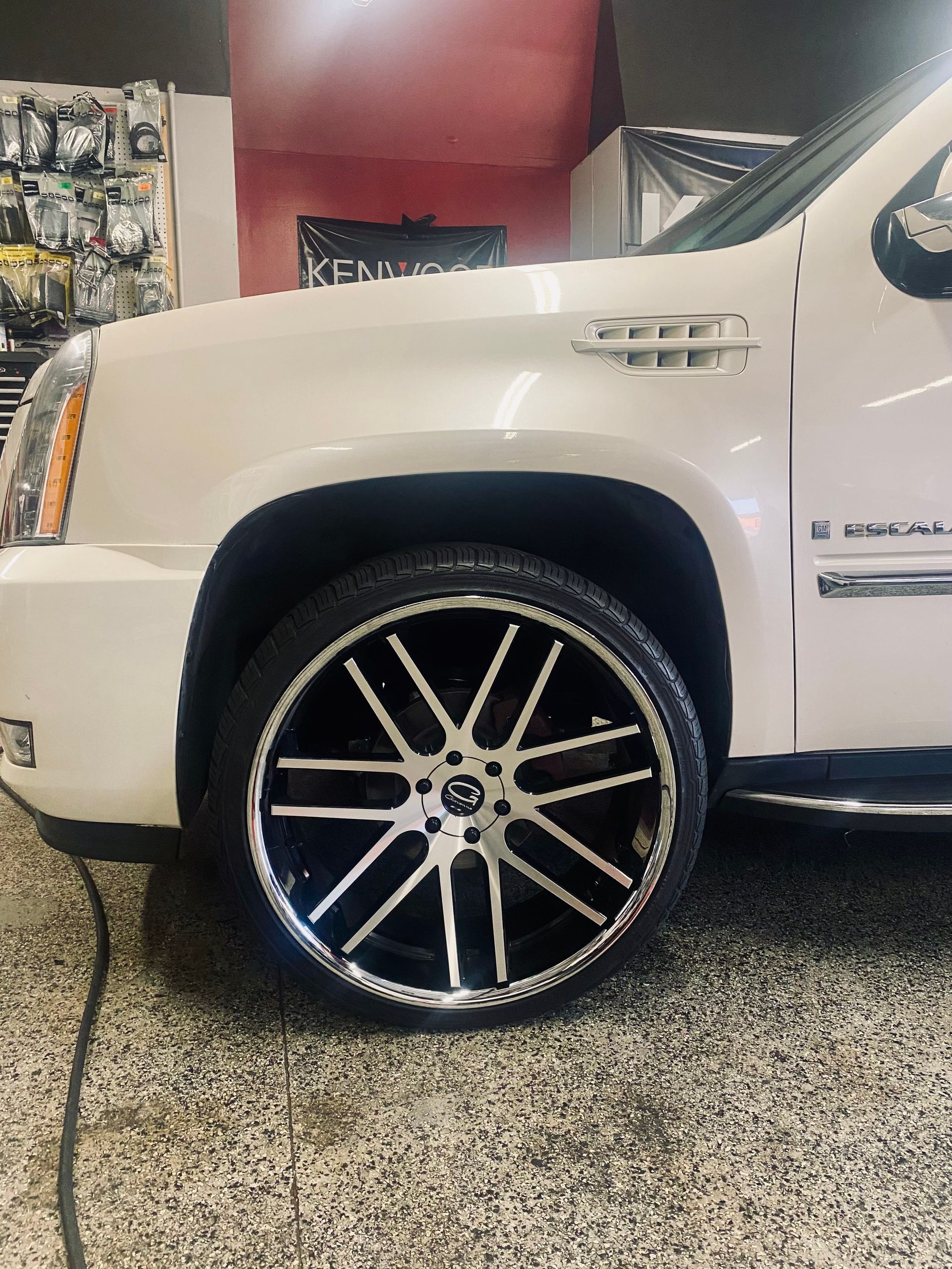 A white suv with black wheels is parked in a garage.