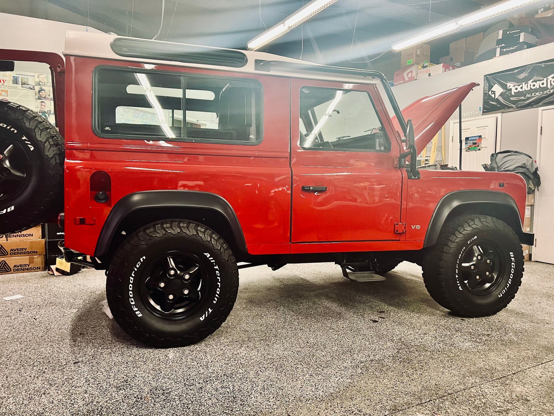 A red jeep with the hood up is parked in a garage.