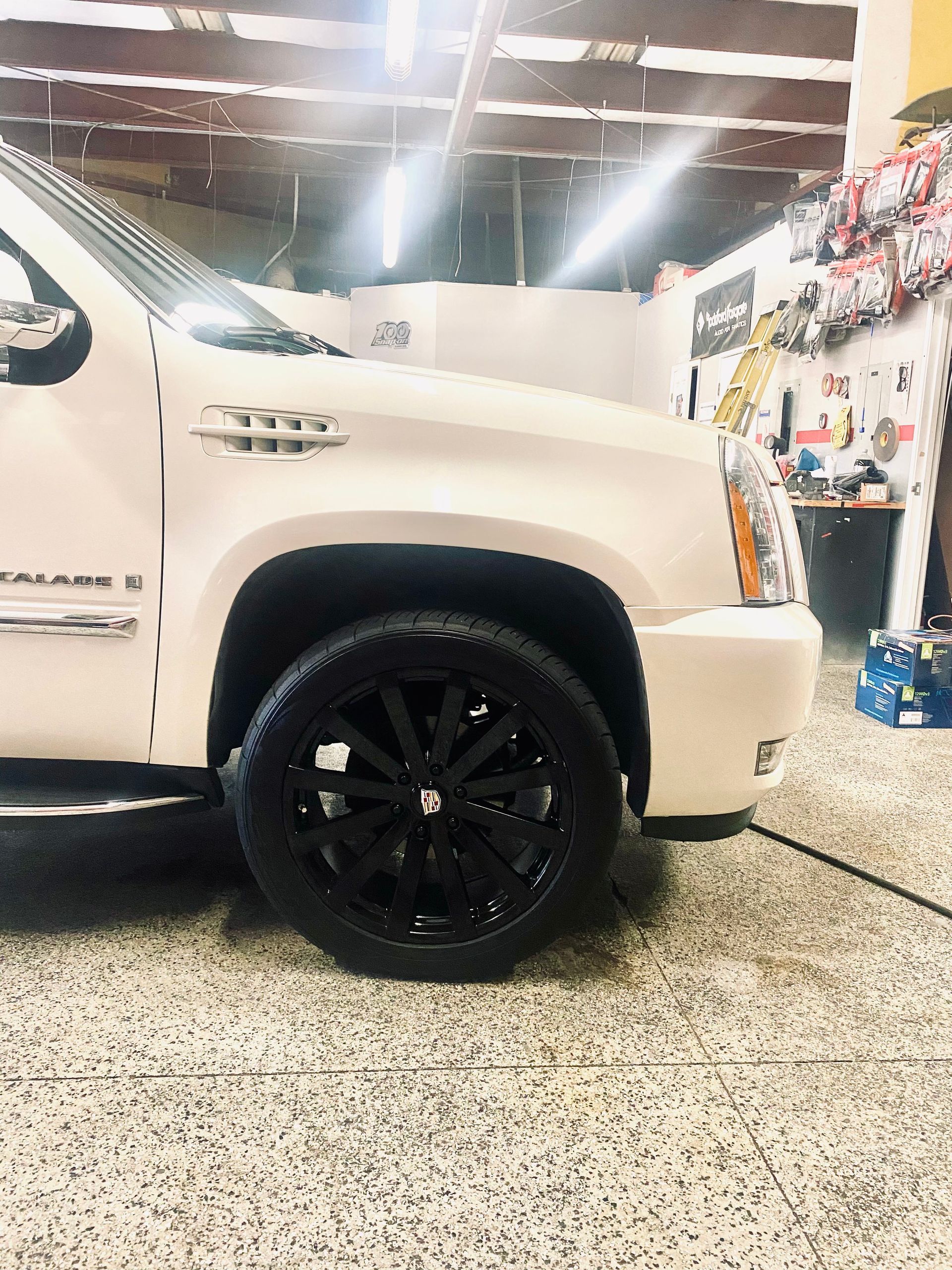 A white truck with black wheels is parked in a garage.