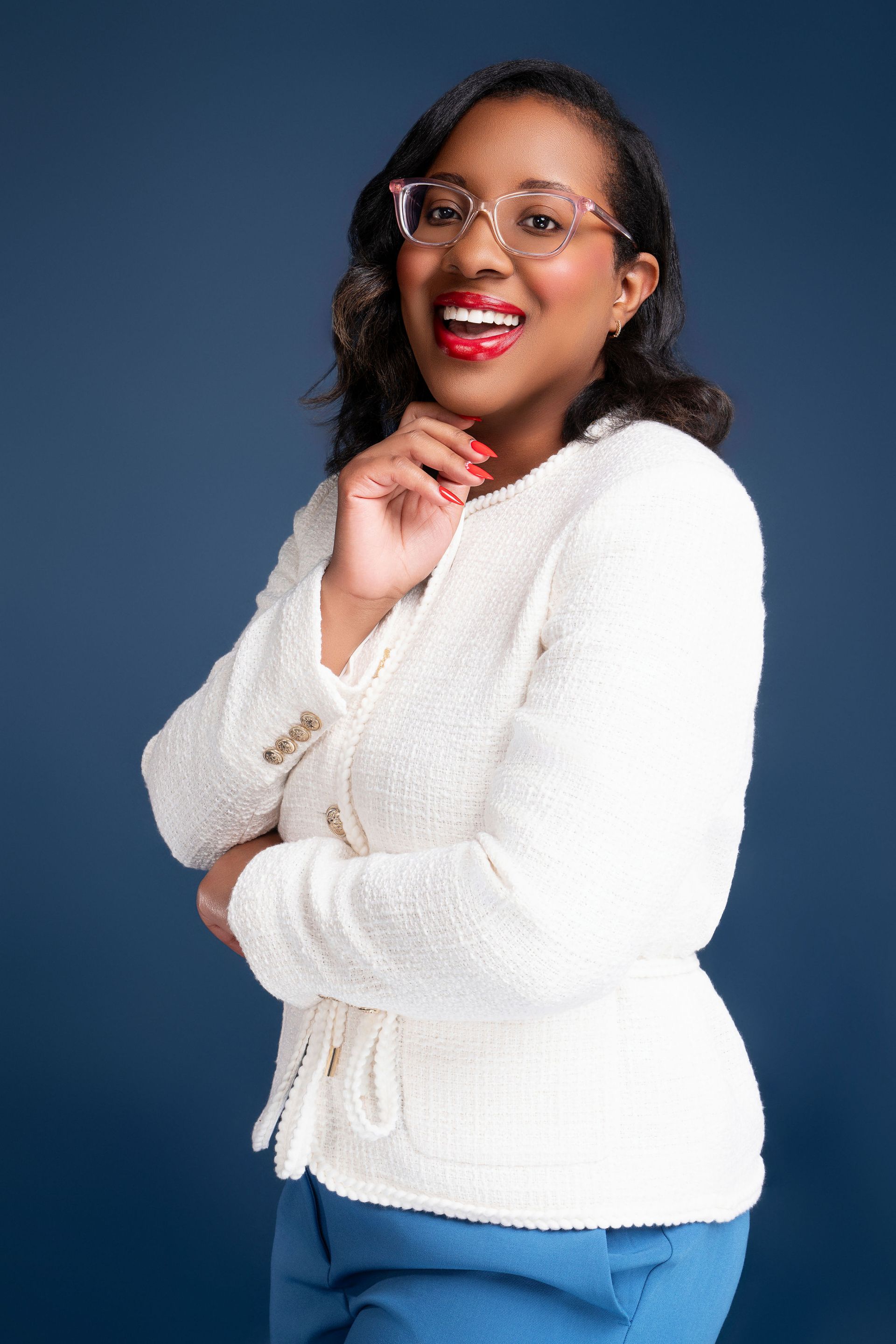 Woman in white suit stands smiling.