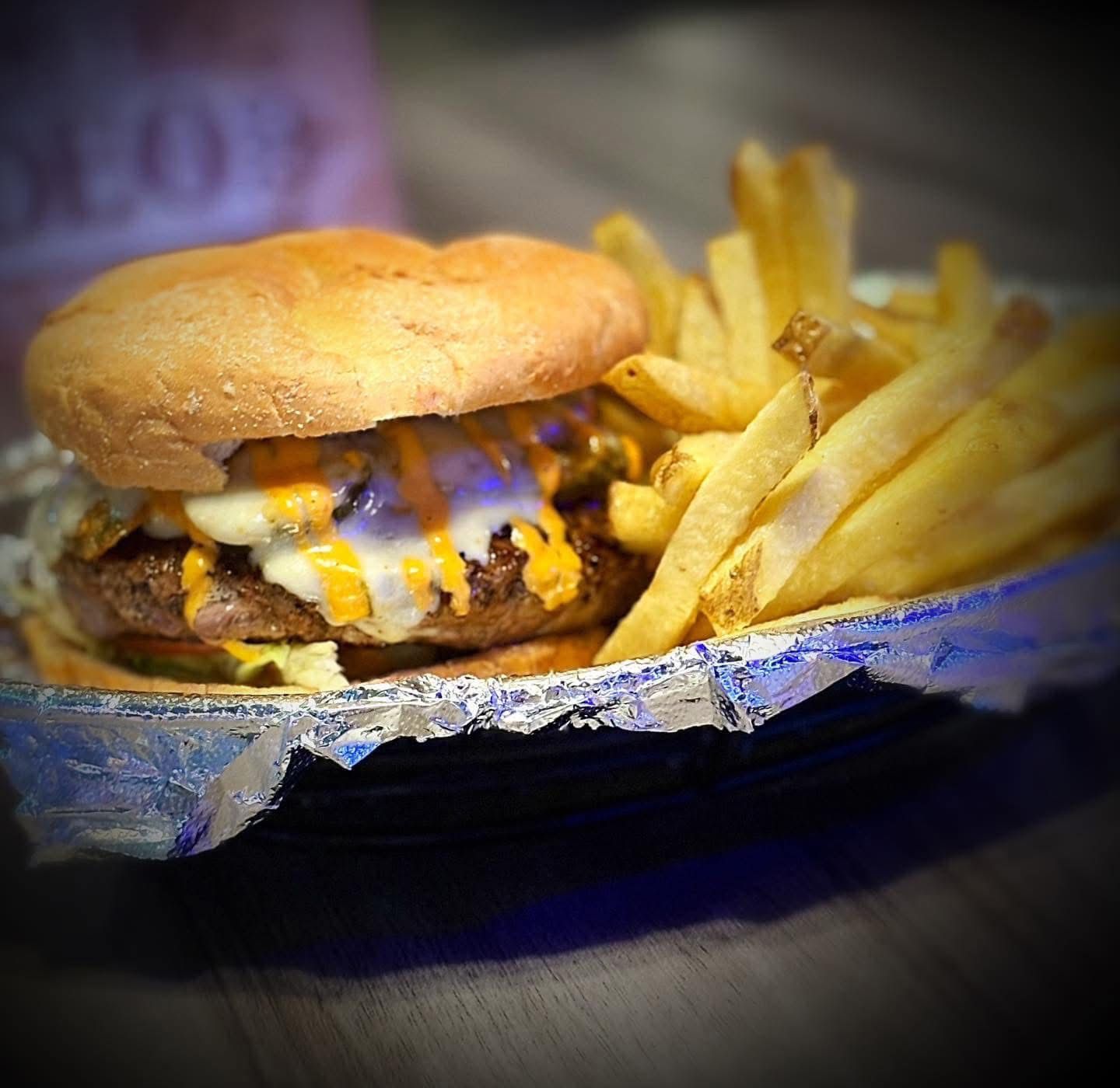 A hamburger and french fries in a tin foil container