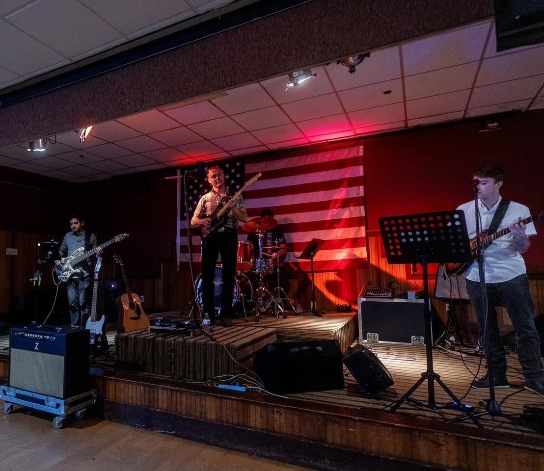 A band is playing on a stage with an american flag in the background