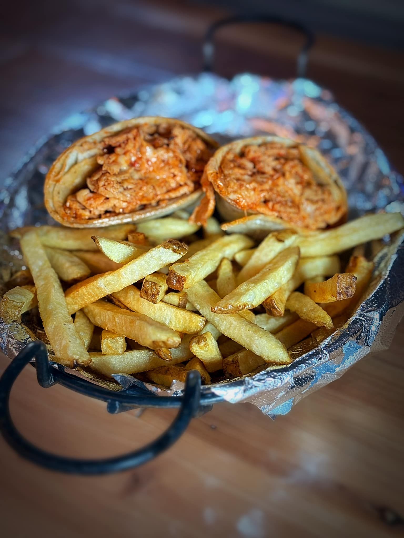 A close up of a tortilla wrap and french fries on a plate.