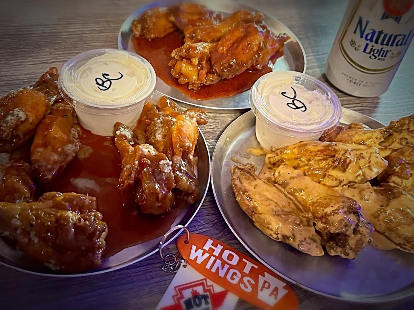 Two plates of chicken wings and french fries on a table.