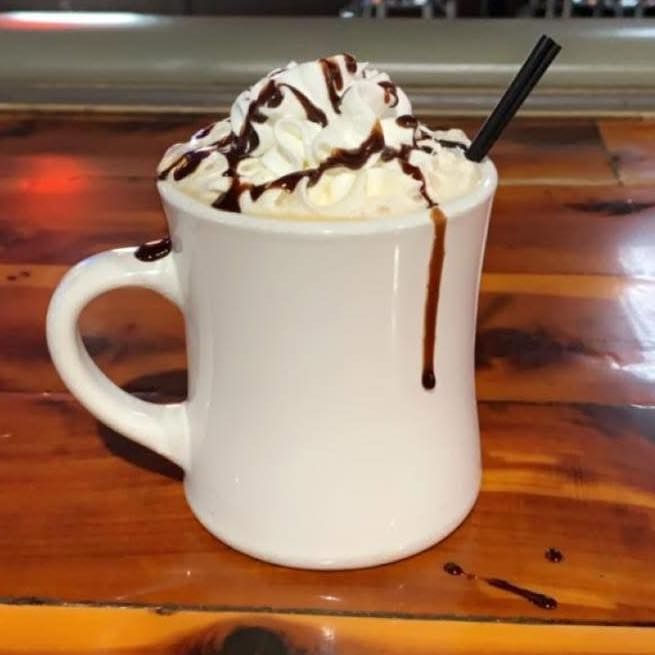 A white mug filled with whipped cream and chocolate sauce