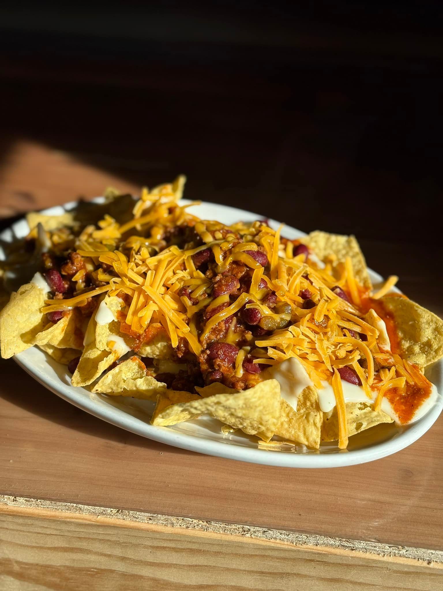 A white plate topped with nachos and cheese on a wooden table.