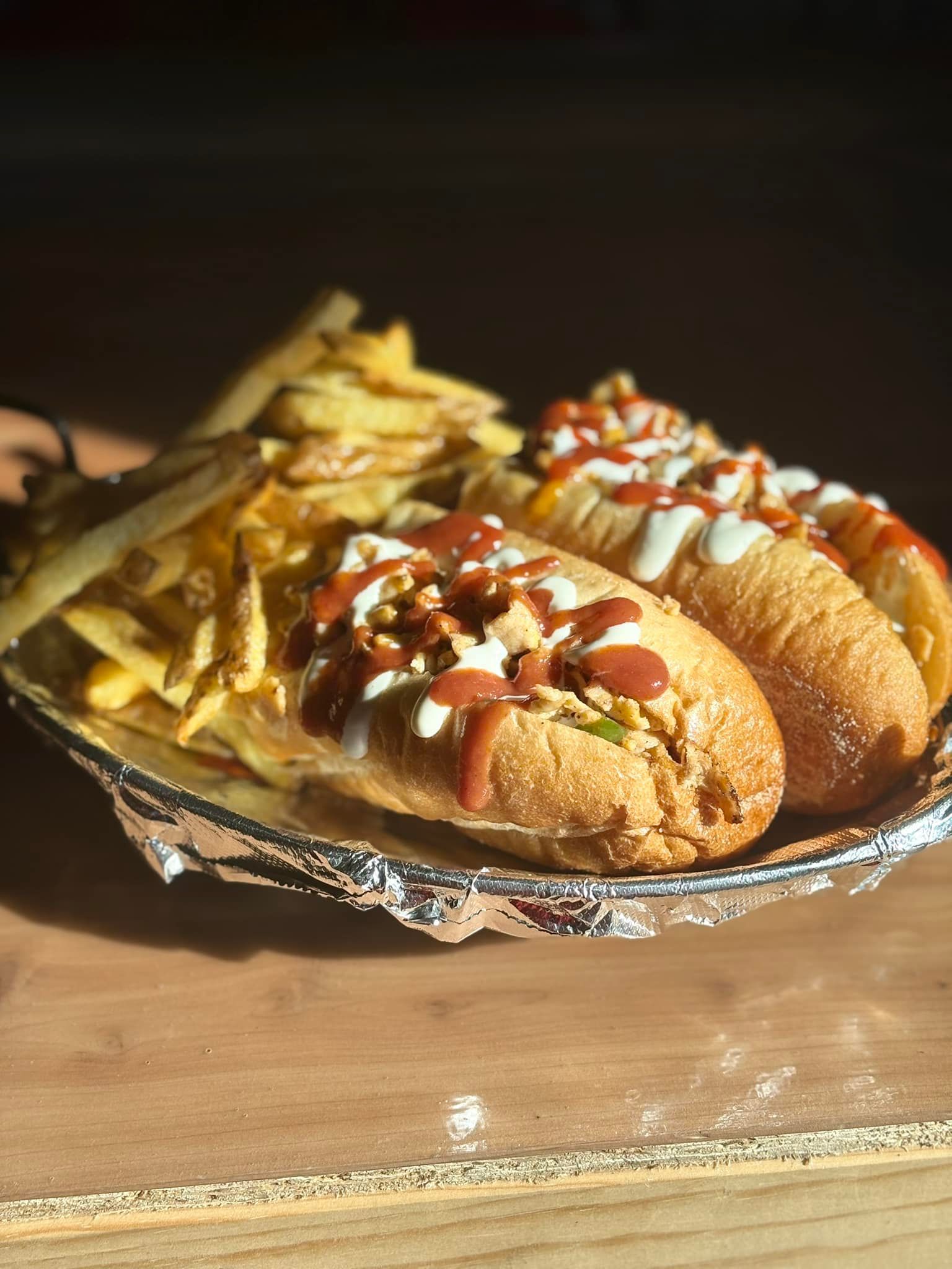 Two hot dogs and french fries on a plate on a table.