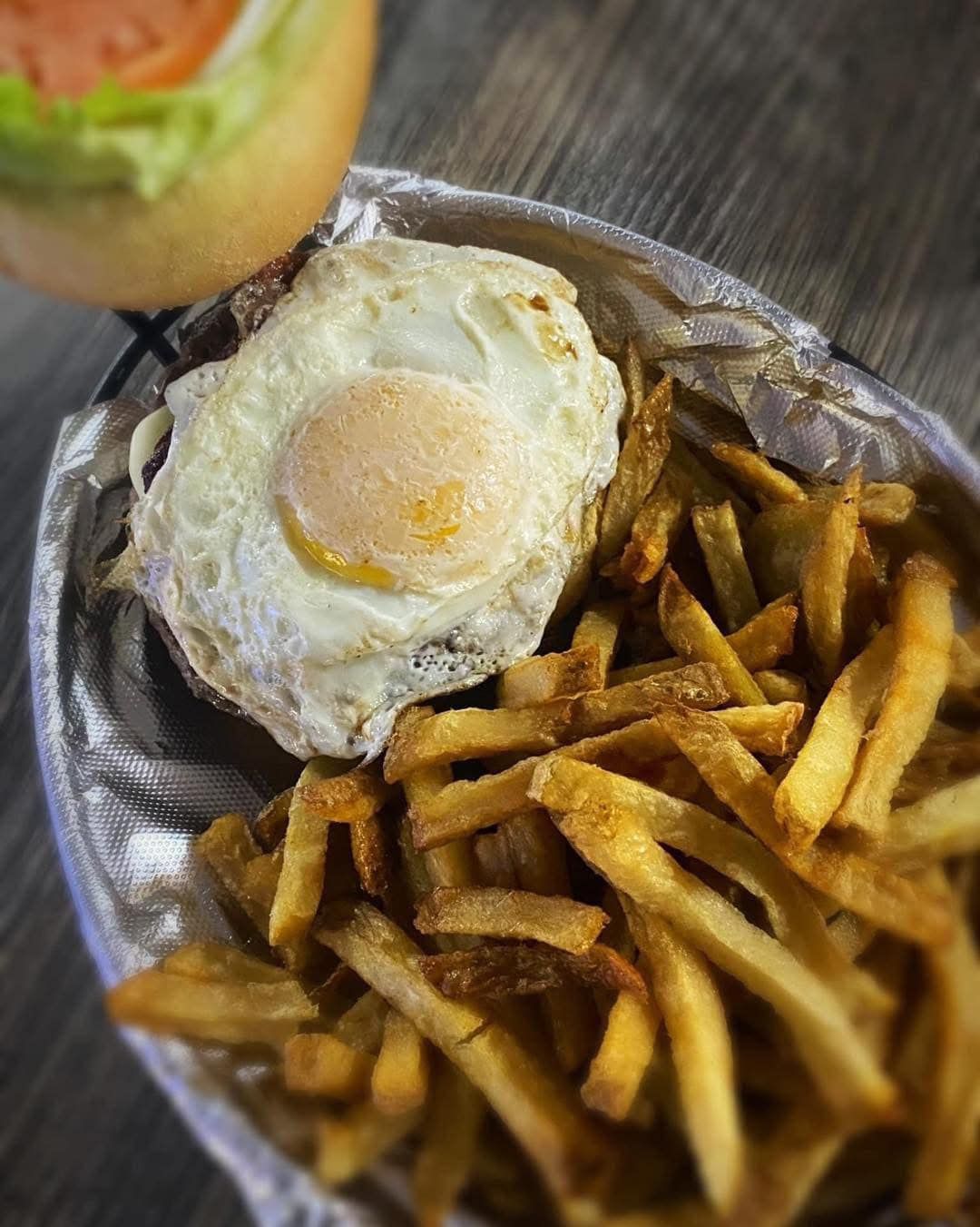 A plate of french fries with a fried egg on top.