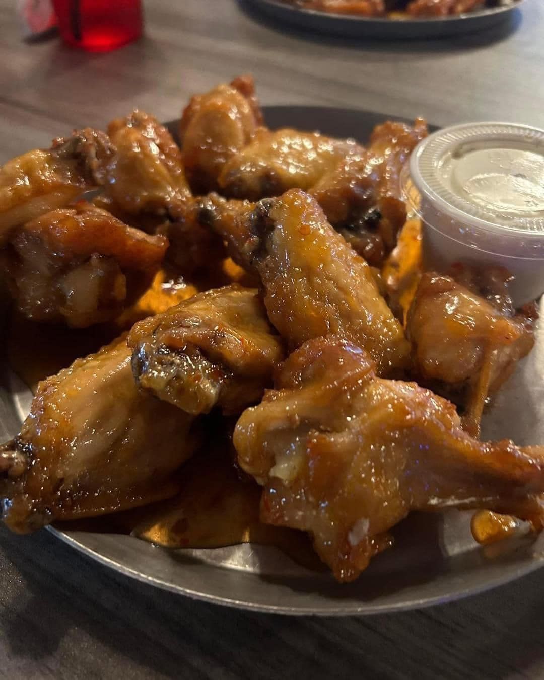 A plate of chicken wings with dipping sauce on a table