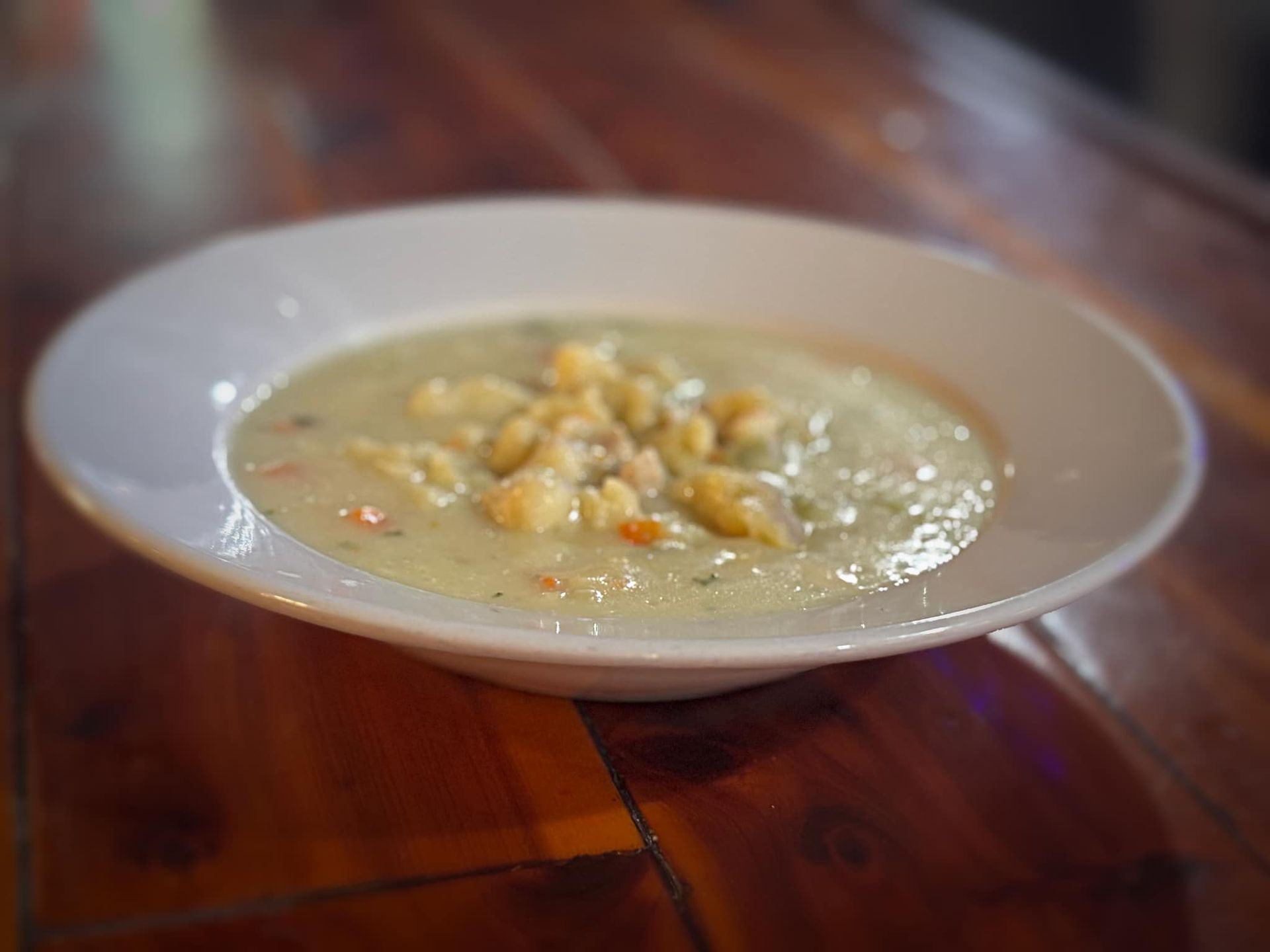 A bowl of soup is sitting on a wooden table.