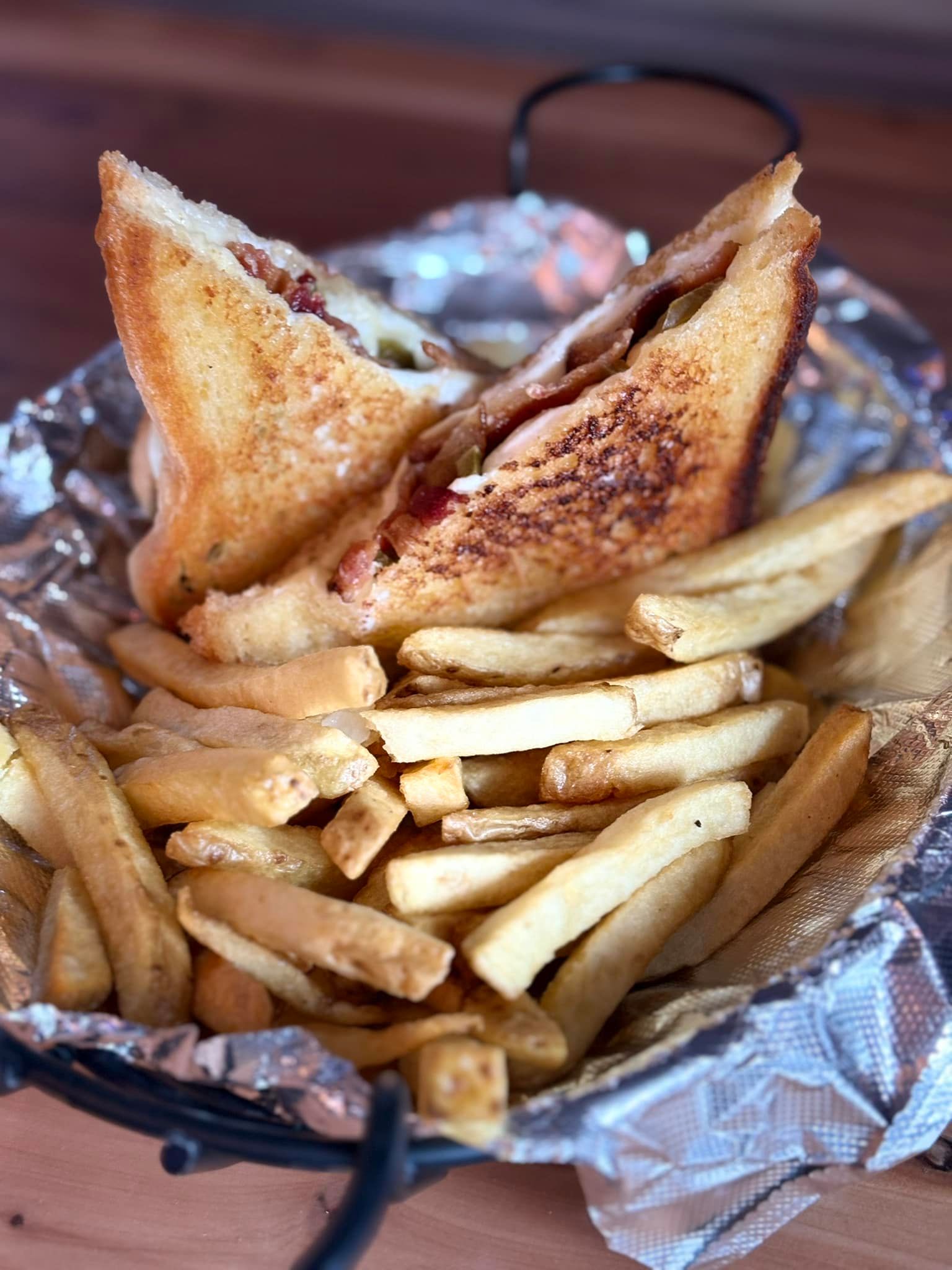 A sandwich and french fries in a basket on a table.