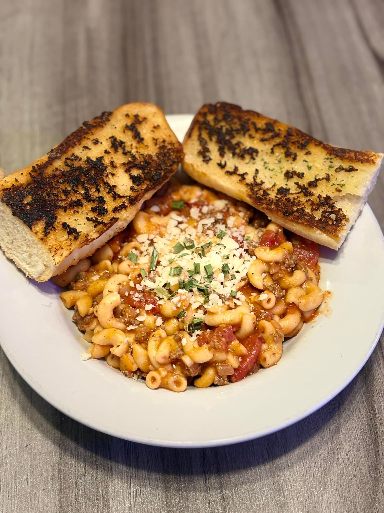 A white plate topped with macaroni and cheese and garlic bread.