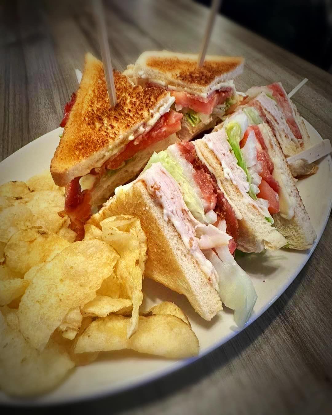 A plate of sandwiches and chips on a table