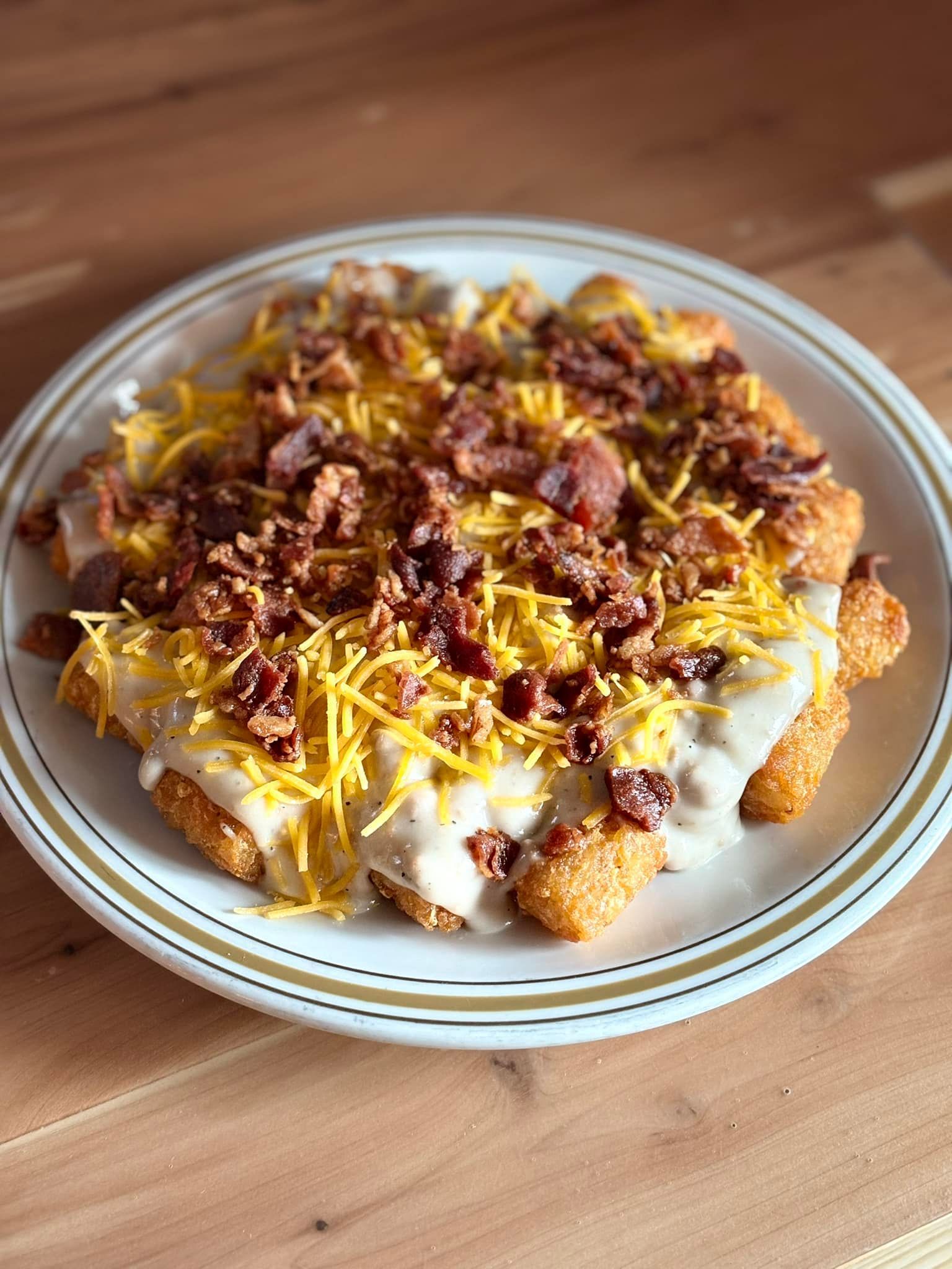 A plate of food with cheese and bacon on a wooden table.