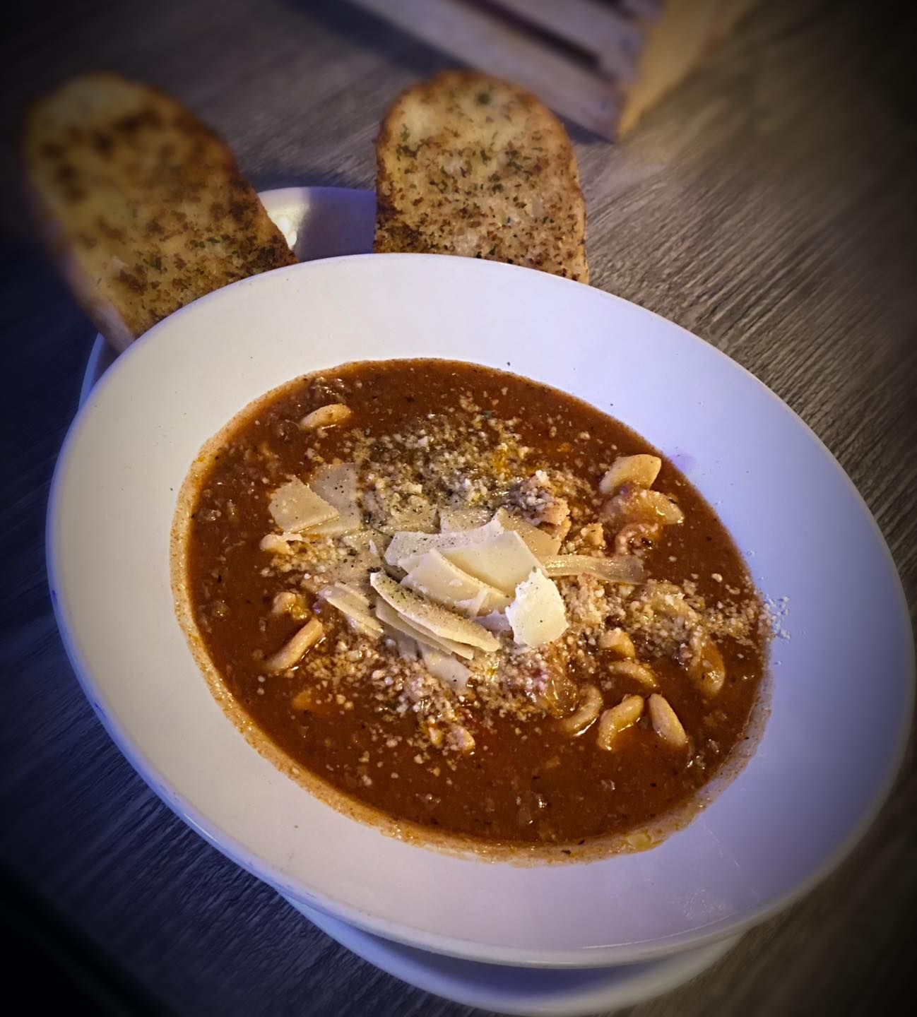 A bowl of soup with garlic bread on the side