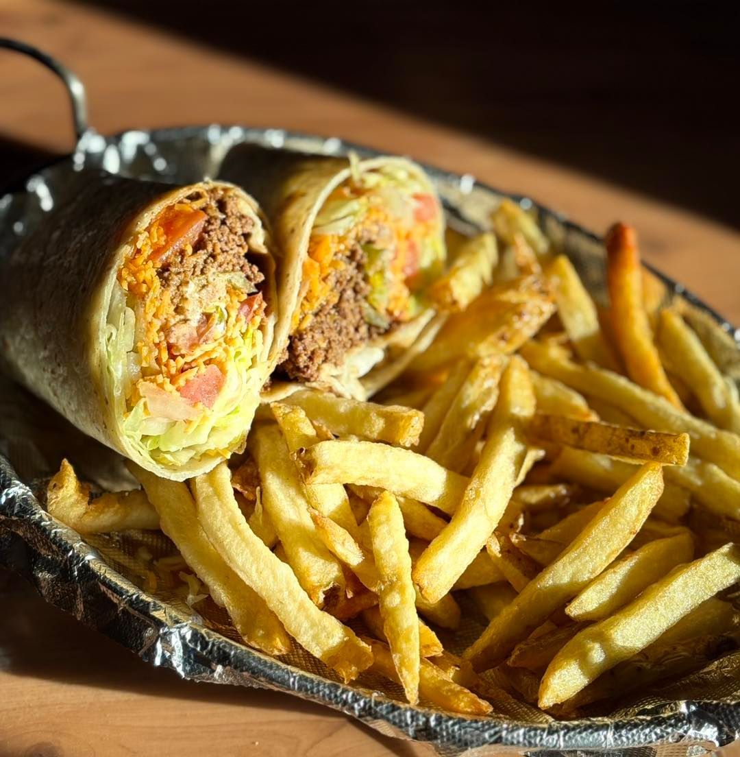 A burrito and french fries in a tin foil container