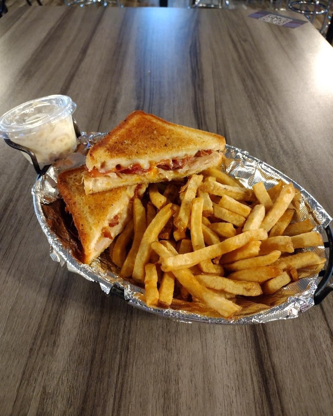 A grilled cheese sandwich and french fries on a plate on a table.