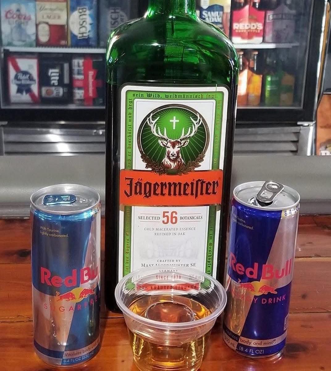 A bottle of jagermeifter next to two cans of red bull