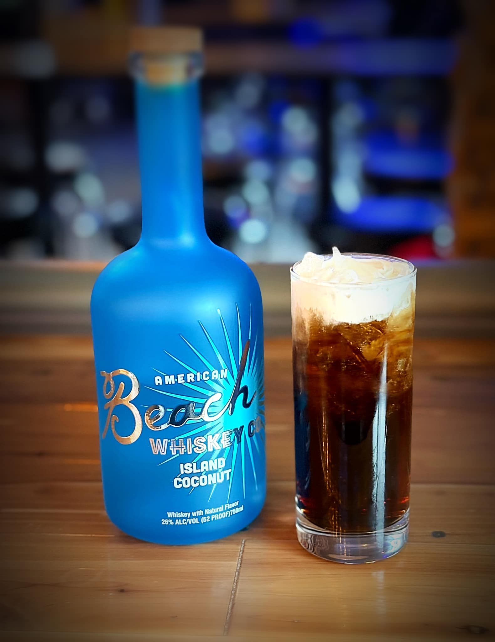 A bottle of beer and a glass of beer are on a wooden table.