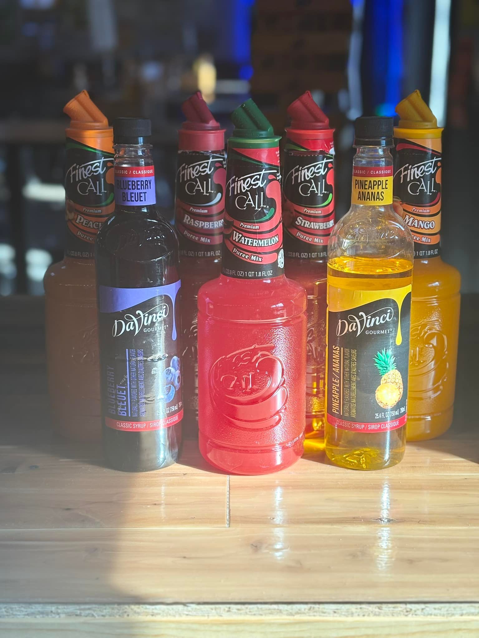 A bunch of bottles of syrup are sitting on a wooden table.