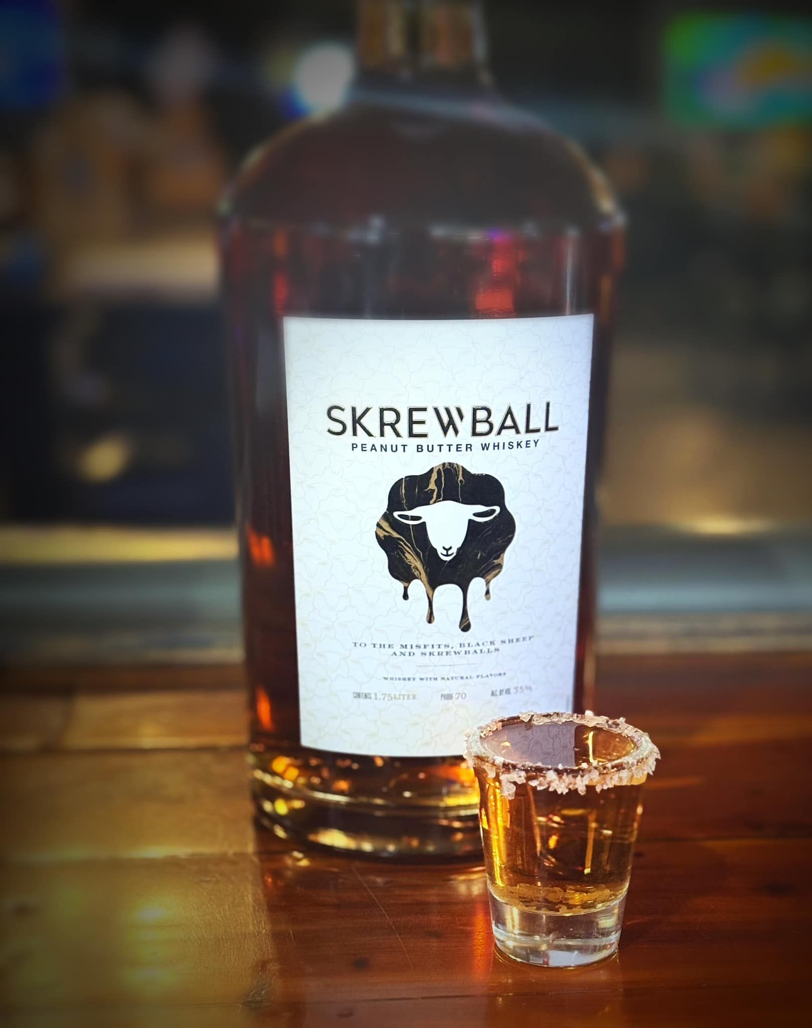 A bottle of skrewball next to a shot glass