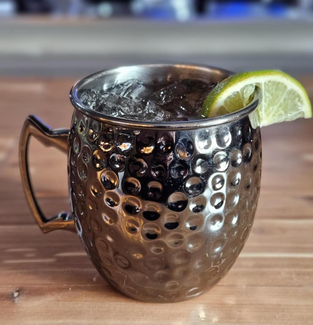 A silver mug filled with ice and a slice of lime