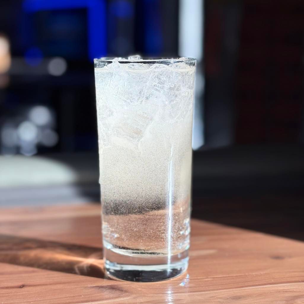 A glass of water is sitting on a wooden table.