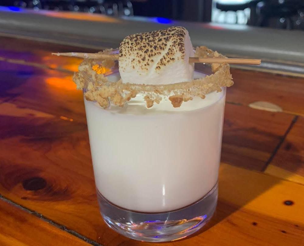 A shot glass filled with a white liquid and a marshmallow on a toothpick.