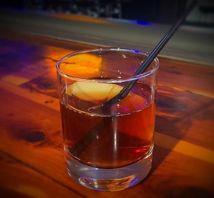 A glass of alcohol with a straw in it on a wooden table