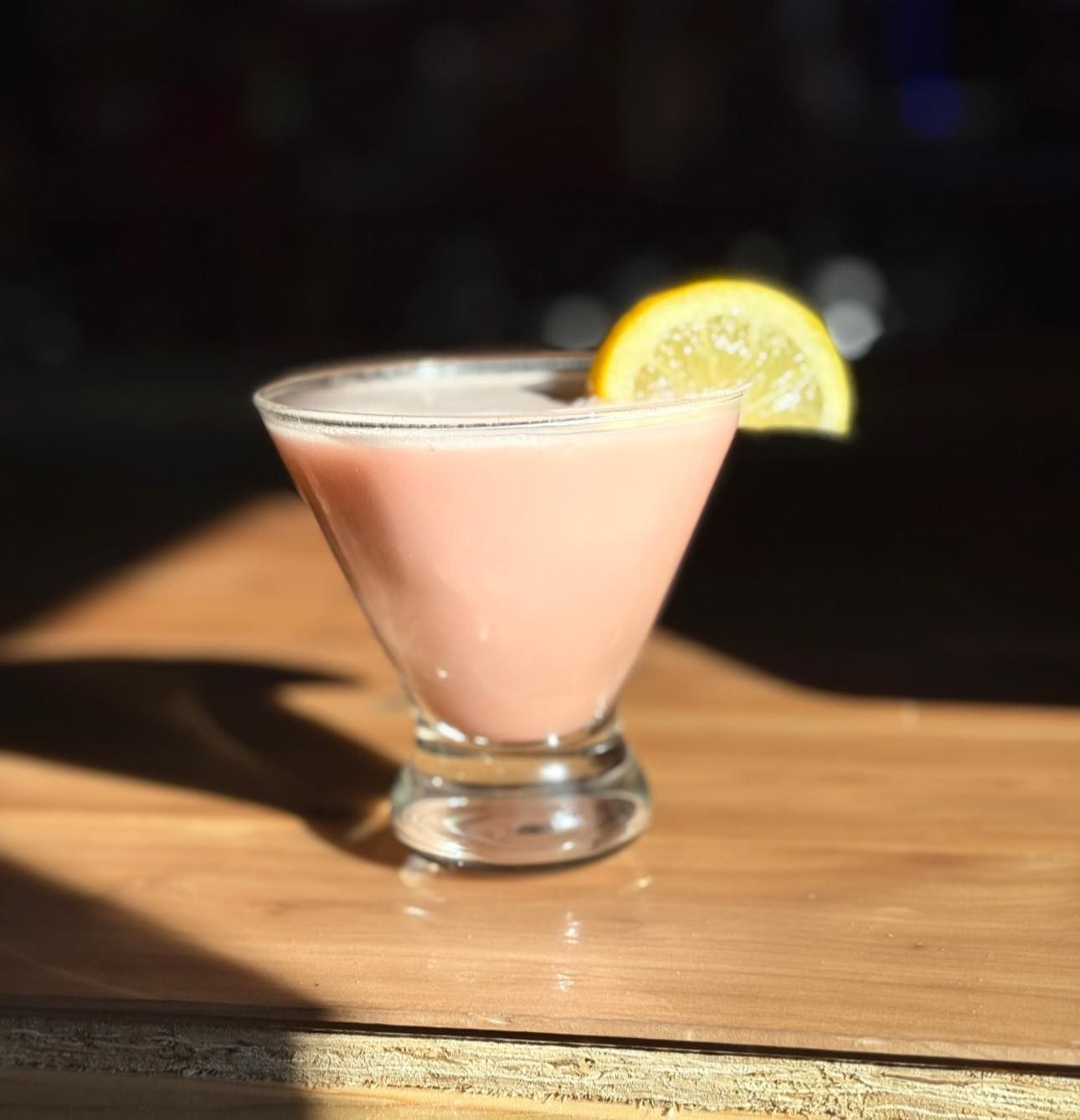 A pink martini with a lemon slice on top