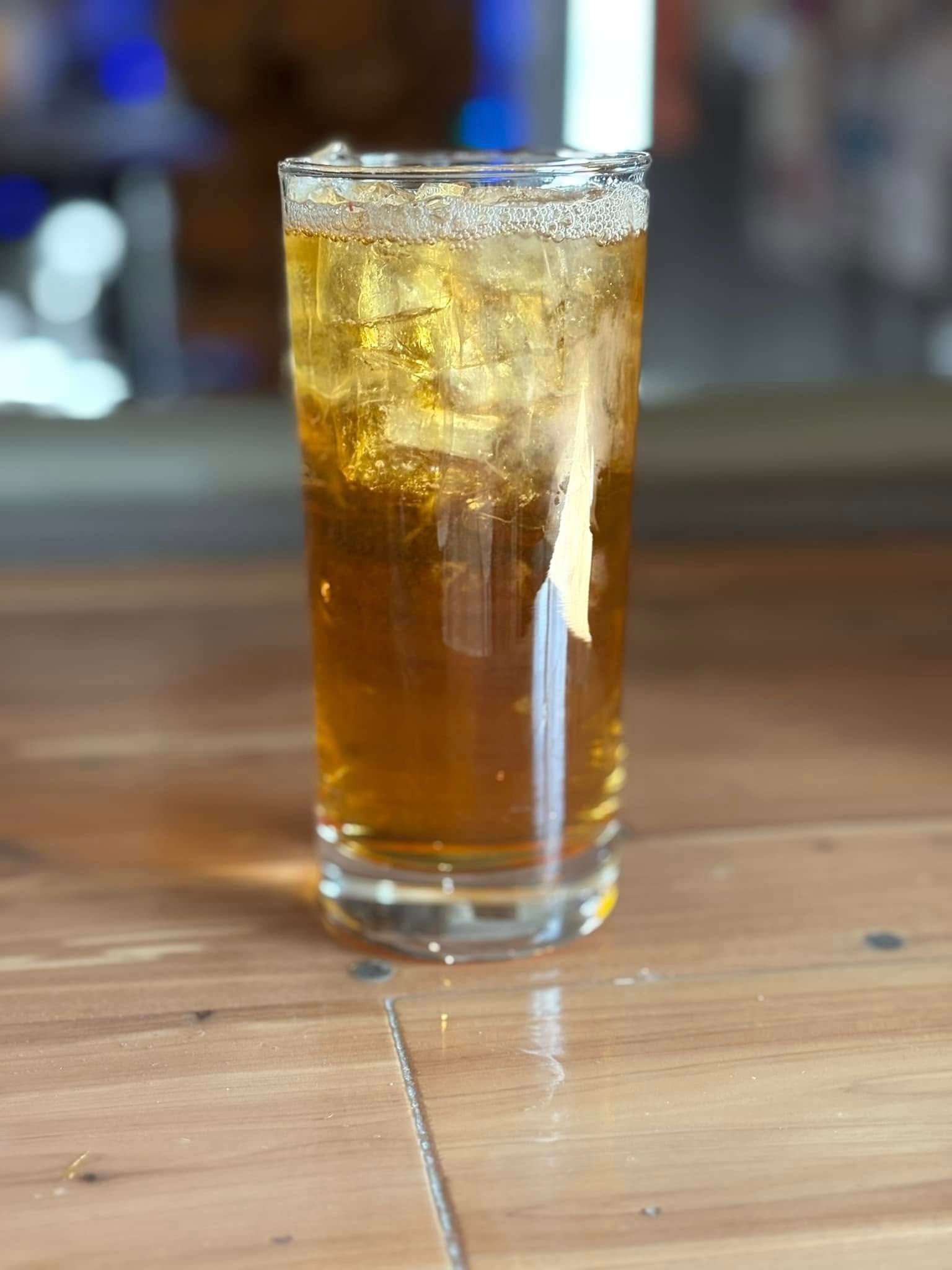 A glass of beer is sitting on a wooden table.