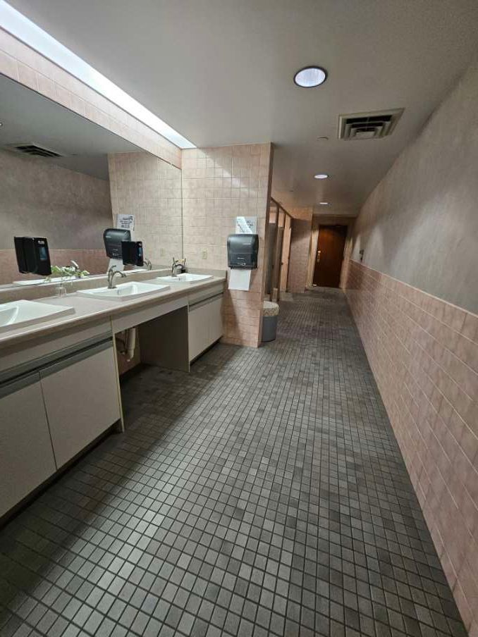 A long hallway leading to a bathroom with sinks and mirrors.