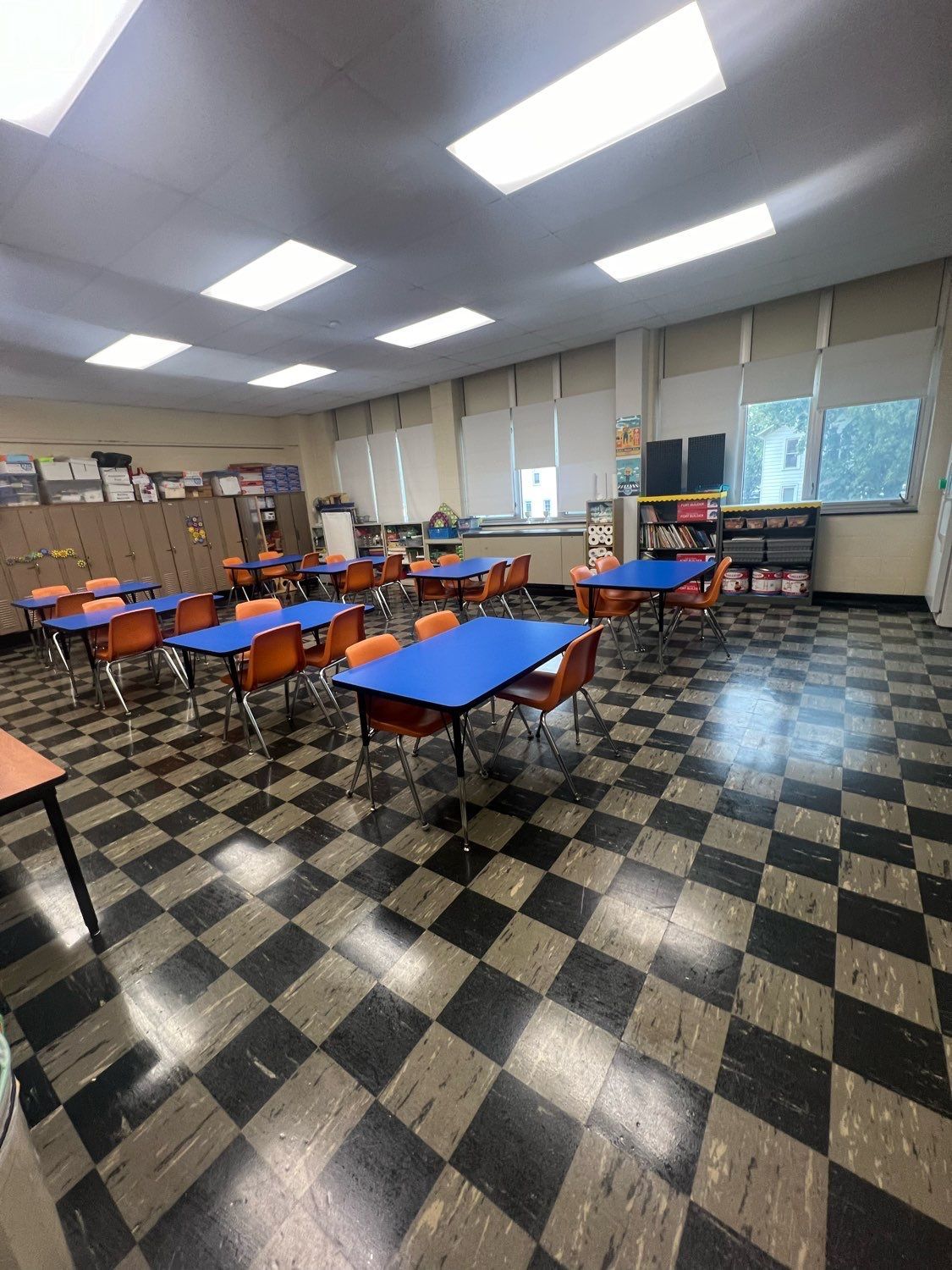 A classroom with tables and chairs and a checkered floor.